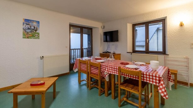A dining area with a table set for four, a television mounted on the wall, and a poster on the wall.