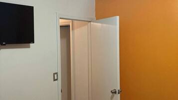 A room with a white door, an orange wall, and a ceiling light.