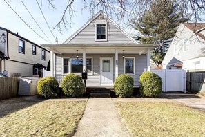 A single-story house with a front porch, a small front yard, and a wooden fence. - House close to JFK NY & Long Island 1st Fl (Uniondale)