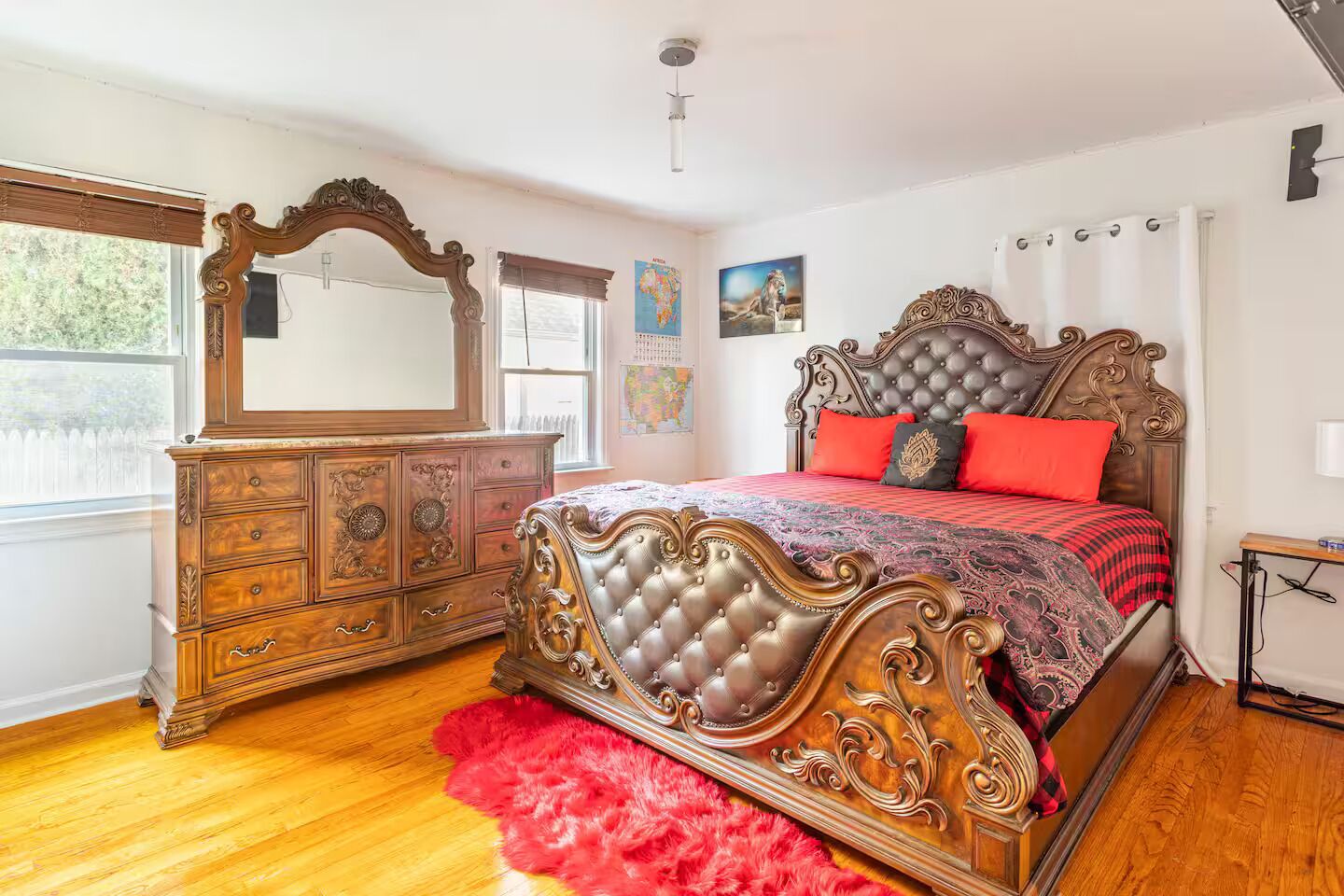 A bedroom with a large bed, ornate dresser, and a mirror.