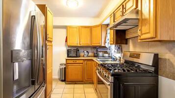 Una cocina con armarios de madera, un refrigerador de acero inoxidable, un microondas, una estufa y un lavamanos.