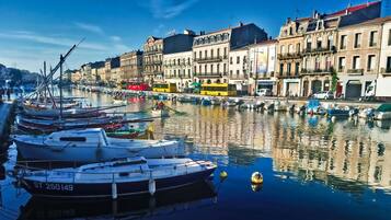 Un canal où sont amarrés des bateaux, des bâtiments le long de la rive et un autobus jaune.