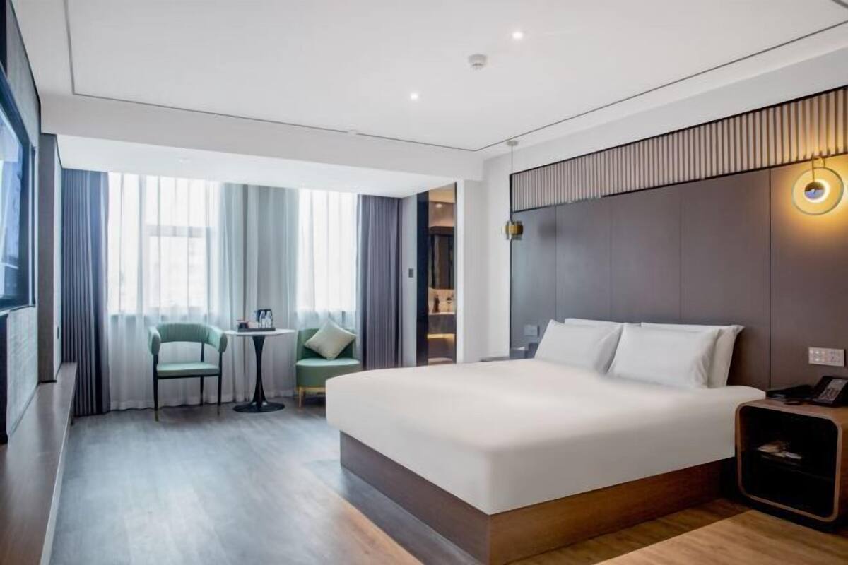 Une chambre d’hôtel moderne avec un grand lit, un petit bureau, une chaise et un téléviseur.