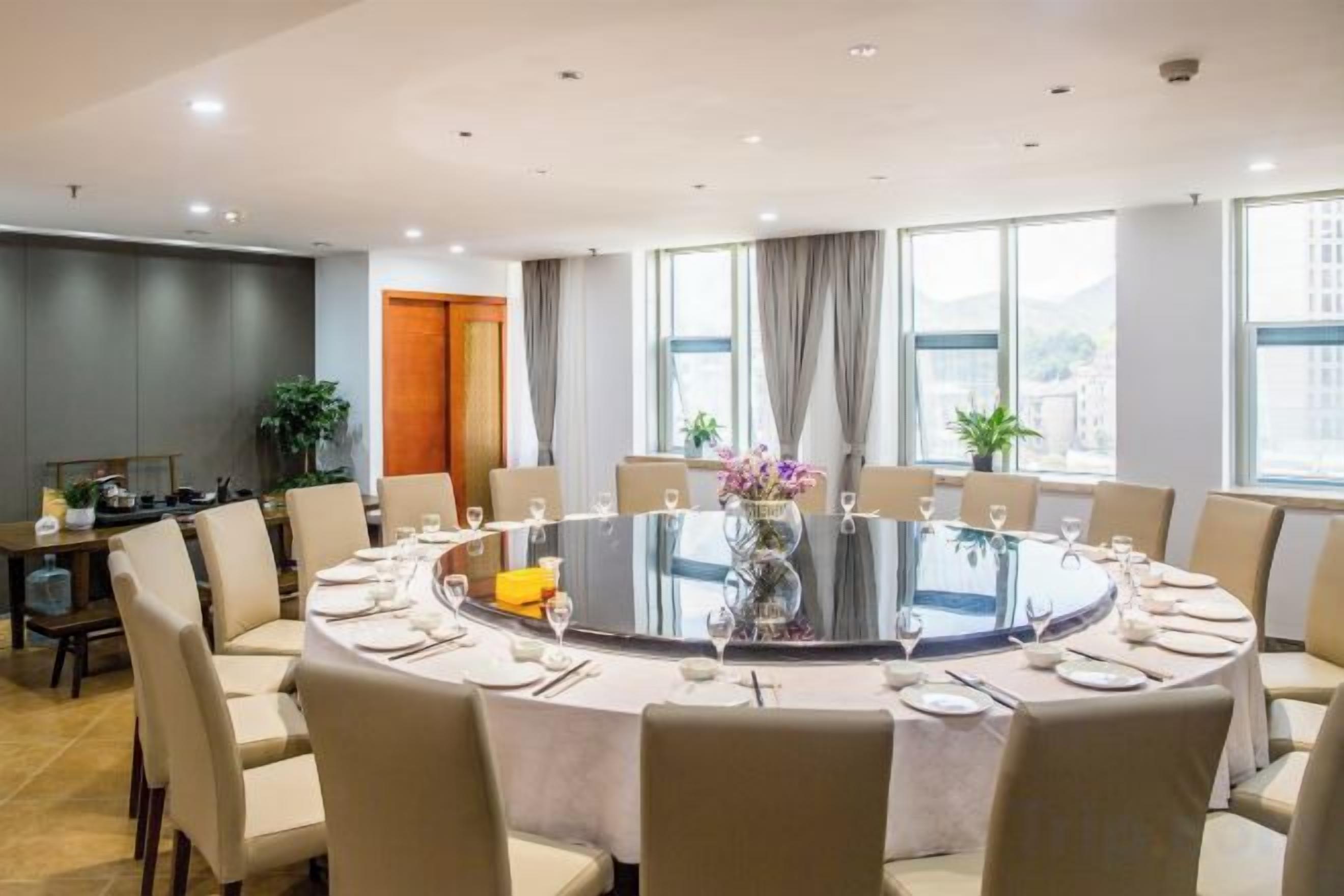 A conference room with a round table, chairs, and a vase with flowers.