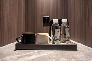 A tray with a black mug, a white mug, and two water bottles on a marble surface. - Kan Hotel (Suichang)
