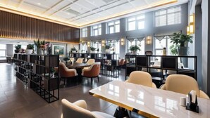 A modern hotel lobby with a spacious layout, featuring multiple seating areas, a central reception desk, and large windows allowing natural light. - Kan Hotel (Suichang)