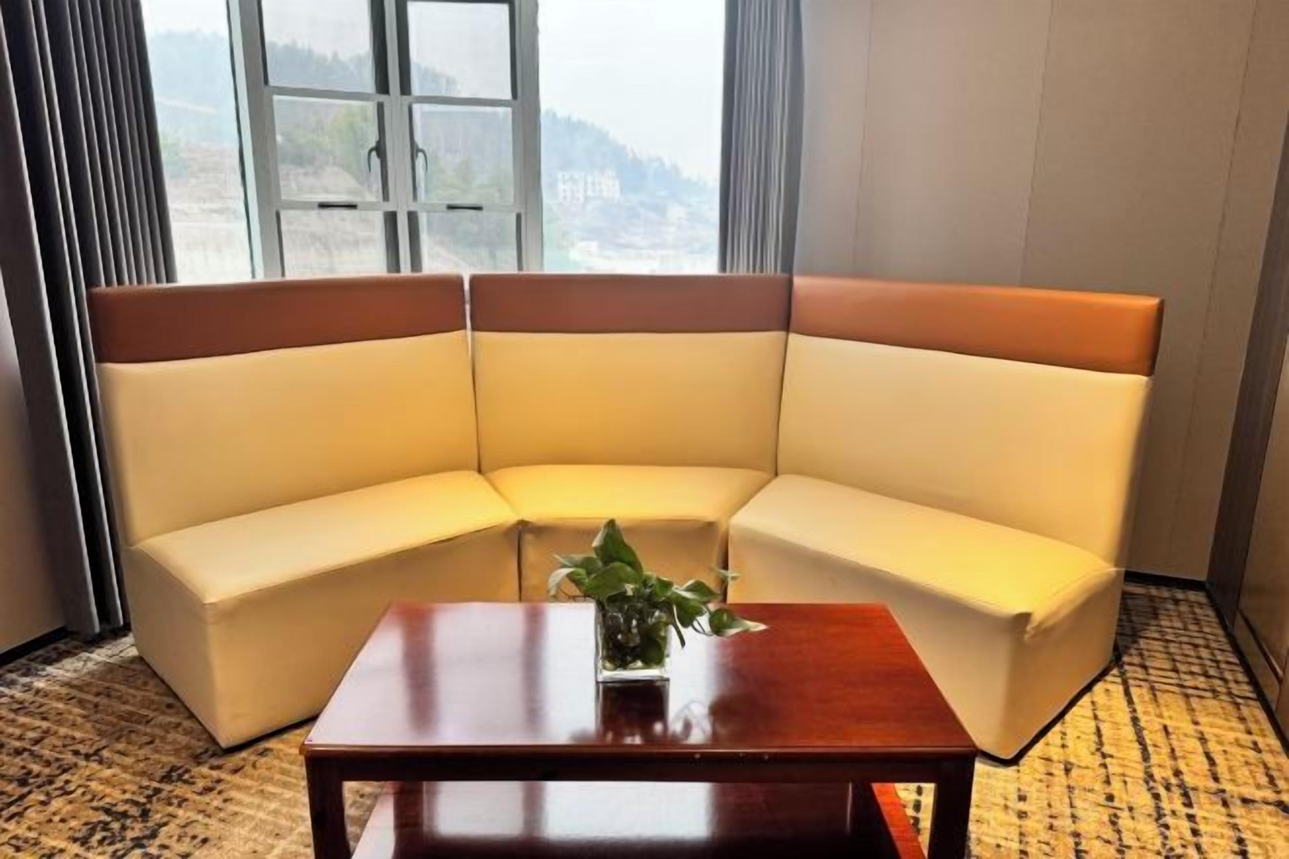 Un sofá de esquina con una mesa de centro de madera en una habitación con un ventanal grande.