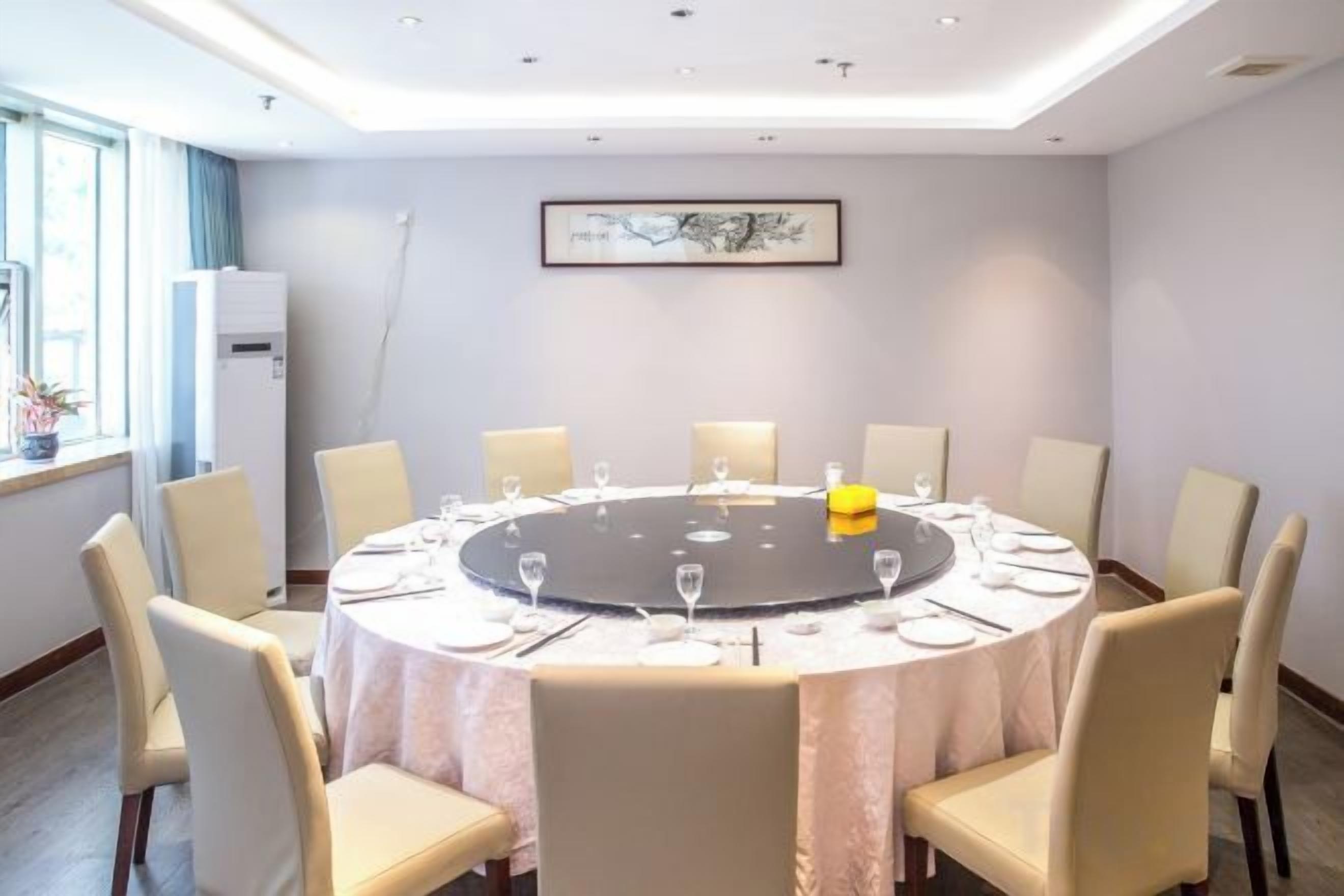 Une salle de conférence avec une table ronde, des chaises et une nappe blanche.