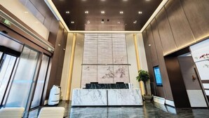 A modern lobby with a marble reception desk, large windows, and a ceiling with recessed lighting. - Kan Hotel (Suichang)