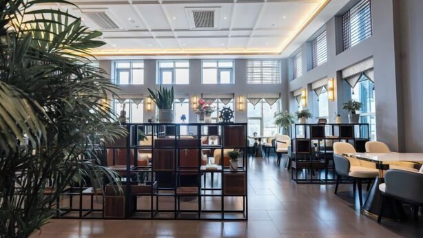 A spacious hotel lobby with high ceilings, large windows, and a central seating area with tables and chairs. - Kan Hotel (Suichang)