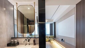 A modern bathroom with a large mirror, a sink, and a vanity. - Kan Hotel (Suichang)