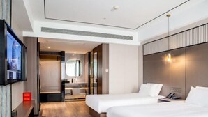 A hotel room with two beds, a TV, a mirror, and a bathroom with a shower and sink. - Kan Hotel (Suichang)