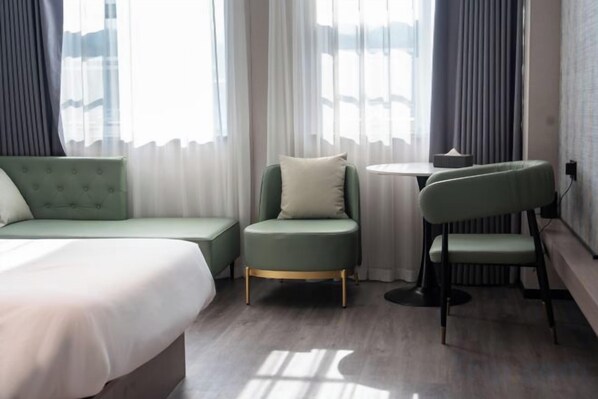 Ein Hotelzimmer mit einem Bett, einem grünen Sofa, einem kleinen Tisch und einem Sessel.