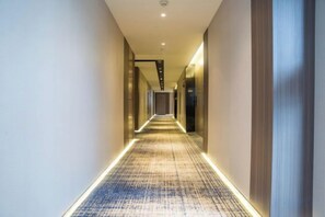 A hotel corridor with a patterned carpet and recessed lighting. - Kan Hotel (Suichang)