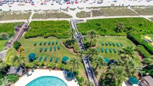 An aerial view of a resort with a pool, sun loungers, and a bridge connecting different areas.