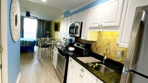 A modern kitchen with white cabinets, stainless steel appliances, and a black countertop.