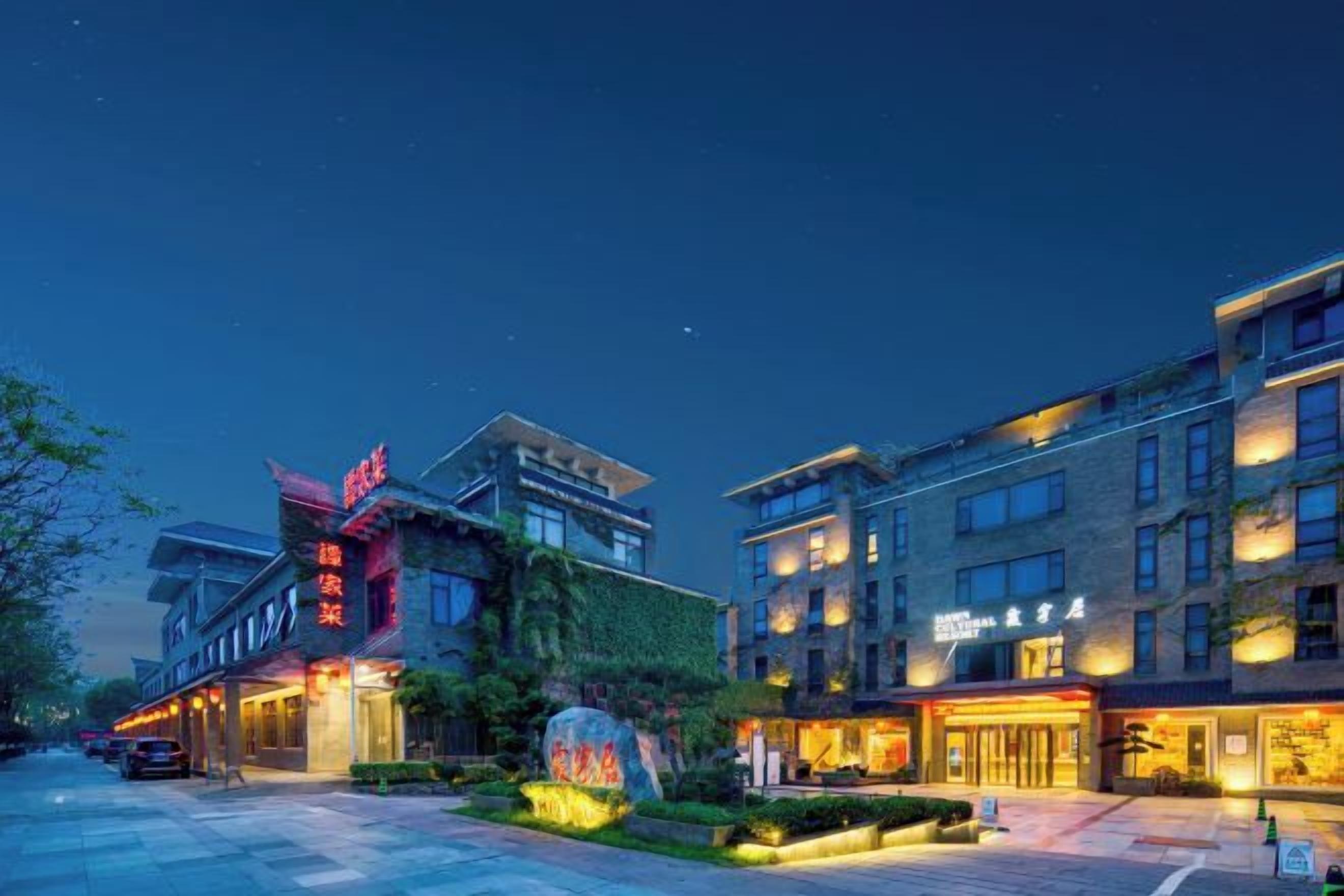 A hotel with multiple floors, a well-lit entrance, and a visible signboard.