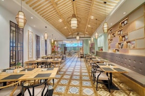 A restaurant with a long counter, multiple tables, and hanging light fixtures. - Ningbo Ninghaixia Guesthouse Hotel (Xuxiake Avenue Branch) (Ninghai)