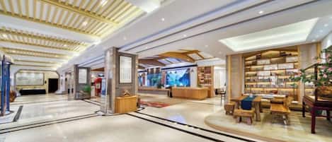 A spacious lobby with a high ceiling, a reception desk, and a seating area with a coffee table.
