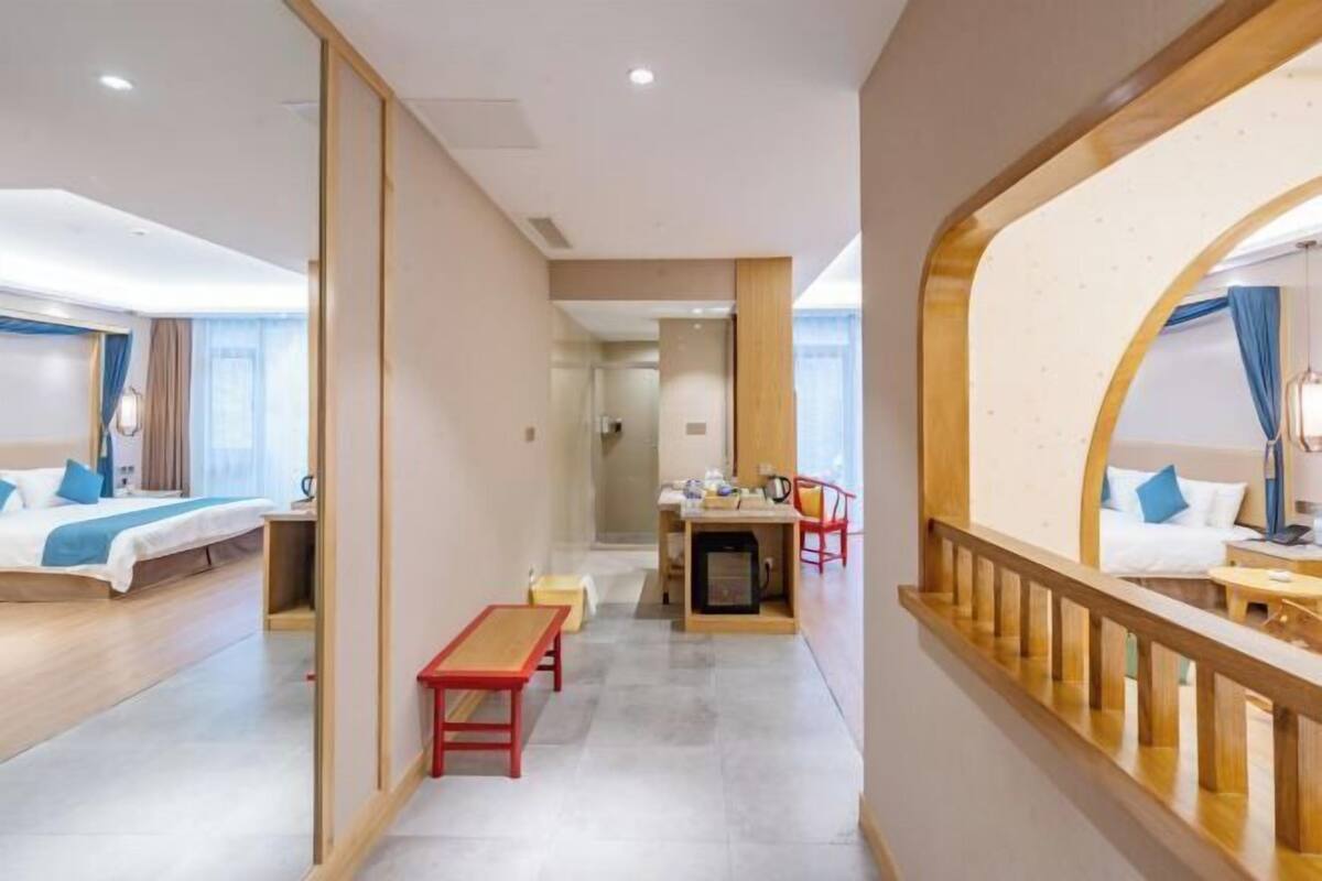 A hotel room with a bed, a desk, a chair, and a small table.