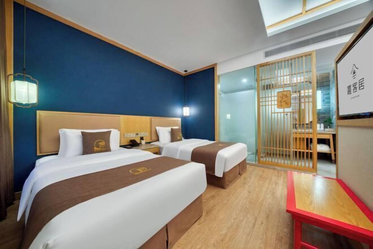 A hotel room with two beds, a desk, and a red table.