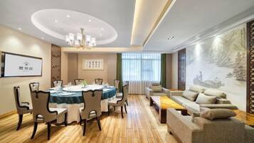 A modern hotel room with a dining area, a sofa, and a mural on the wall.