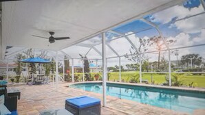 A pool area with a covered patio, a ceiling fan, and a view of the surrounding landscape. - Heated Pool/cozy/highly recomended/premier host/Elegant/close to many activities (Cape Coral)