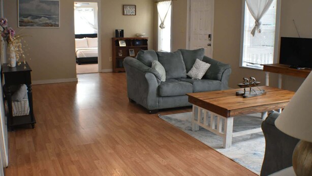 A living room with a grey sofa, wooden coffee table, and a bookshelf. - Cozy Coastal Getaway (Ingleside)