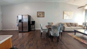 A modern living room with a dining area, a sofa, a coffee table, and a refrigerator. - Chapel Summary:<br>🏡 Wel (Ingleside)
