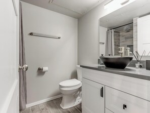Ein modernes Badezimmer mit Toilette, großem Spiegel und einem schwarzen Waschbecken.