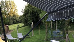Un bain à remous avec vue sur une cour arrière verdoyante et un espace patio avec des chaises.