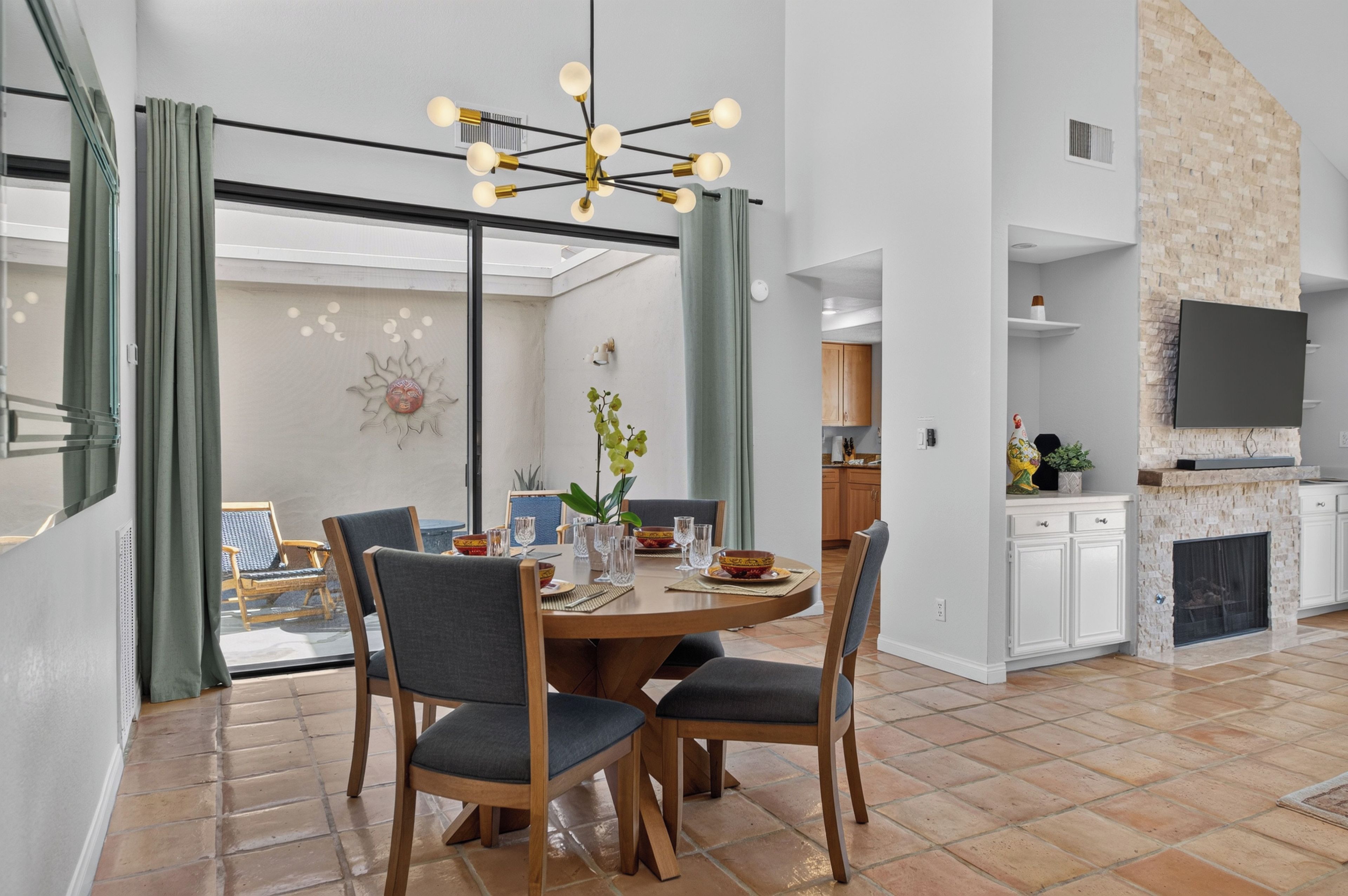 A modern dining area with a round table, two chairs, and a chandelier.