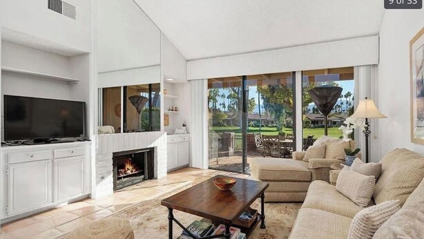 A modern living room with a fireplace, comfortable seating, and a large TV.