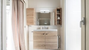 A modern bathroom with a wooden vanity, a glass shower enclosure, and a built-in shelf. - Il Ginepro - Suite Cactus (Pula)
