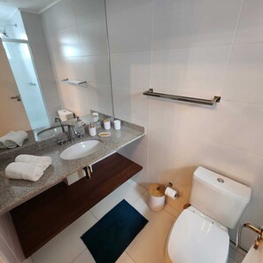 Une salle de bain moderne avec un double vasque, un miroir, un porte-serviettes et des toilettes.