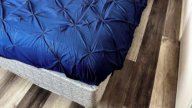 A bed with a blue quilt and pillows, a wooden headboard, and a wooden floor. - Kid & Pet Friendly Farm Guesthouse (Golden Valley)
