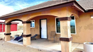 A two-story building with a flat roof, a front door, and a covered porch area with two chairs. - Kid & Pet Friendly Farm Guesthouse (Golden Valley)