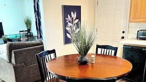 A dining area with a round wooden table, four chairs, a potted plant, and a painting on the wall. - Kid & Pet Friendly Farm Guesthouse (Golden Valley)