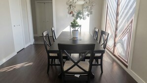 A dining room with a dark wood table and chairs, a potted plant, and a decorative mirror on the wall. - Silver Oak Luxe Stay | King Bed | Retreat (Arrow Creek)