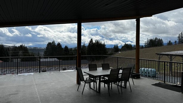 An outdoor patio with a table and chairs, a covered area, and a view of a mountainous landscape. - Silver Oak Luxe Stay | King Bed | Retreat (Arrow Creek)