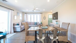 Un espacio habitable amplio con una mesa de comedor, sillas de mimbre, un sofá y un ventilador de techo.