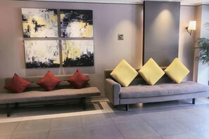 A reception area with a grey sofa, red and yellow cushions, and abstract art on the wall. - Home Inn Select (Shanghai Zhoupu Wanda Plaza Branch) (Shanghai)