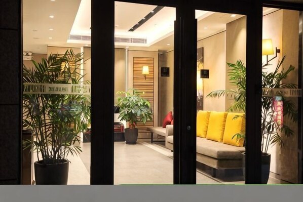 A reception area with a sofa, potted plants, and a wall-mounted lamp. - Home Inn Select (Shanghai Zhoupu Wanda Plaza Branch) (Shanghai)