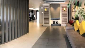 Um lobby moderno com balcão de recepção, área de estar e arranjo de plantas decorativo.
