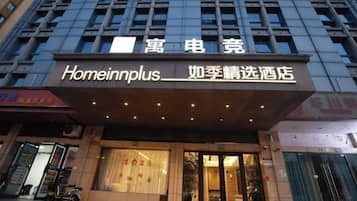 Entrada de hotel com placa 'Homeinnplus' e uma placa menor com '如季精选酒店'.