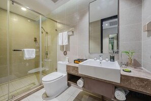 Une salle de bain moderne avec une douche à parois de verre, des toilettes blanches, un grand lavabo et un miroir.