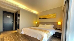 Une chambre d’hôtel avec un grand lit, deux tables de chevet, une tête de lit et un tableau au mur.