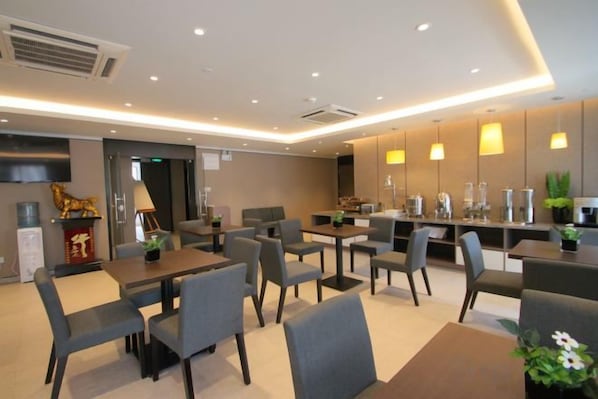 A modern hotel dining area with tables and chairs, a reception desk, and a decorative plant. - Home Inn Select (Shanghai Zhoupu Wanda Plaza Branch) (Shanghai)