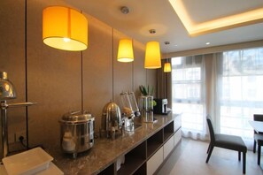 Une cuisine moderne dotée d’un plan de travail en marbre, d’appareils électroménagers en acier inoxydable et de luminaires suspendus.