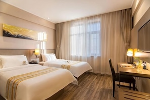 Ein Hotelzimmer mit zwei Betten, einem Schreibtisch, einem Stuhl und einem Fernseher.